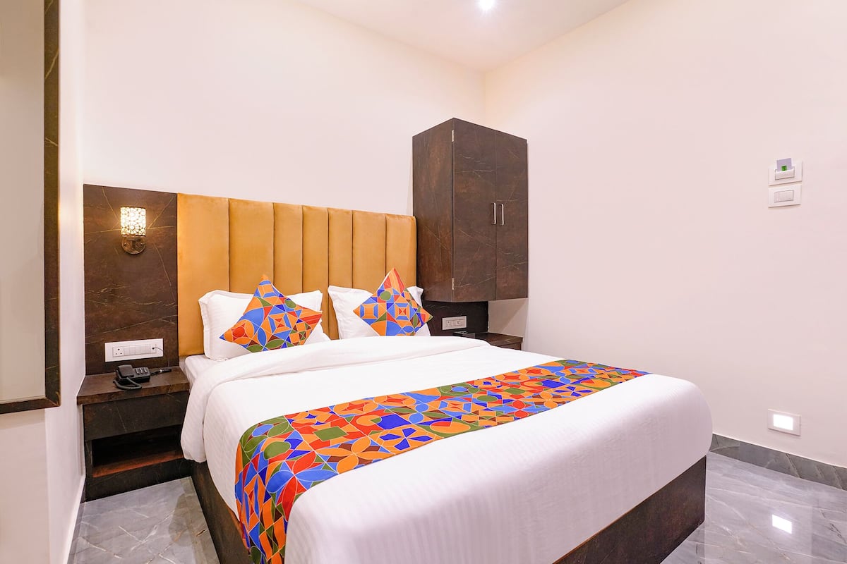A hotel room with a bed, a nightstand, a wardrobe, and a wall-mounted light fixture.
