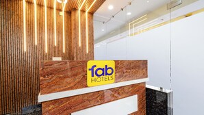 A reception desk with a wooden panel design and a marble counter. - Fabhotel Dlf Inn (Hyderabad)