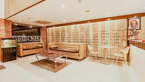 A spacious living room with a large sofa, a coffee table, and a small dining area with chairs. - Fabhotel The Kailash Dev (New Delhi)