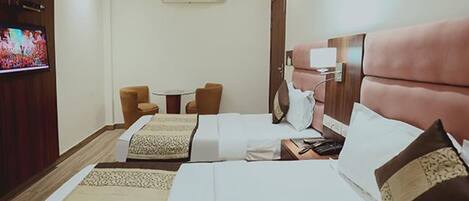 A hotel room with two beds, a TV, a small table, and two chairs.