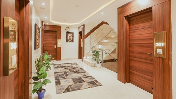 A hallway with wooden doors, a clock, and a staircase. - Fabhotel The Kailash Dev (New Delhi)