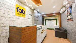 A hotel reception area with a marble wall, wooden reception desk, and a sofa. - Fabhotel Vivaah Inn (New Delhi)