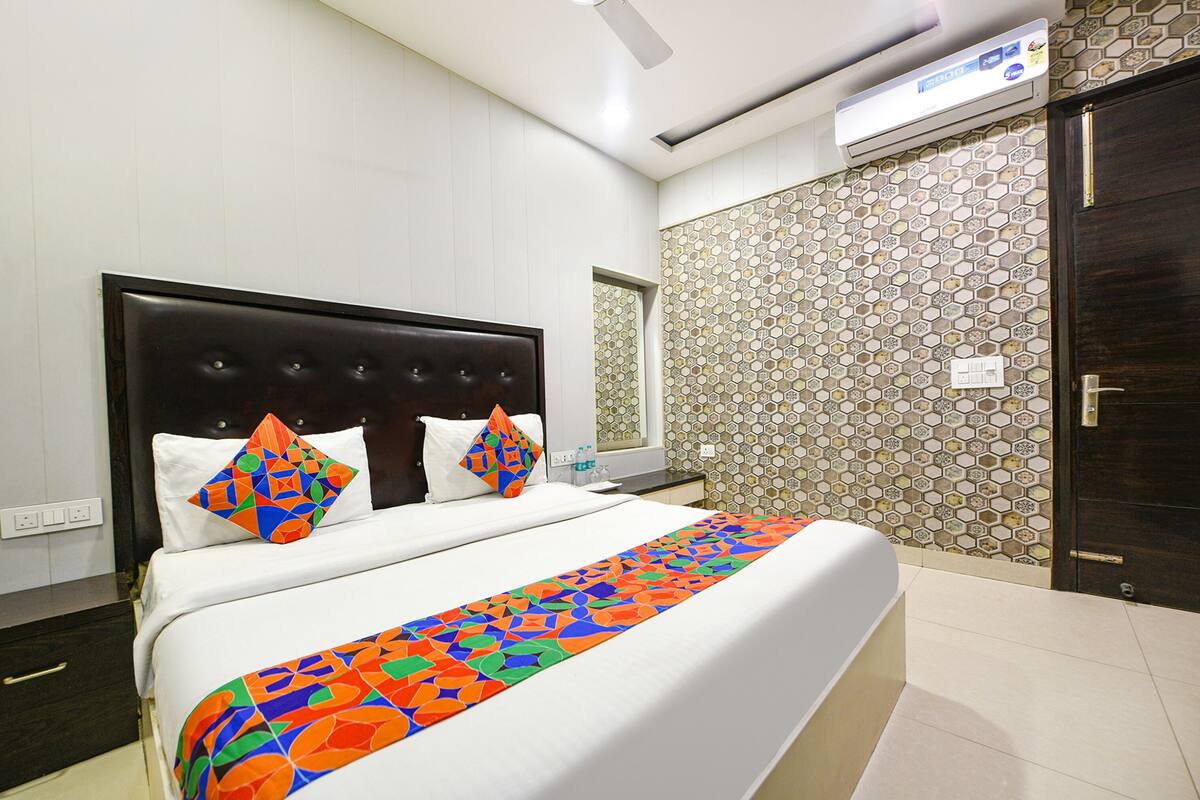 A hotel room with a bed, a nightstand, a mirror, and a door.