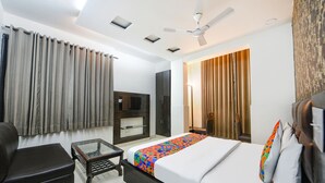 A hotel room with a bed, a desk, a chair, a ceiling fan, and a TV. - Fabhotel Vivaah Inn (New Delhi)