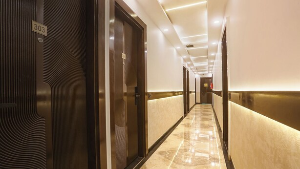 A modern hotel corridor with a marble floor, dark wooden doors, and recessed lighting. - Fabhotel Sugar Inn (New Delhi)