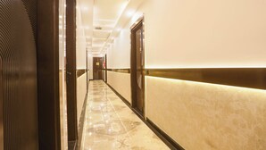 A hotel corridor with a marble floor, a reception area with a counter, and doors leading to rooms. - Fabhotel Sugar Inn (New Delhi)