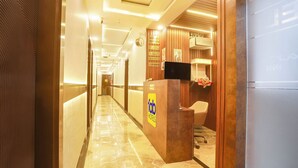 A hotel reception area with a marble floor, wooden reception desk, and a check-in counter. - Fabhotel Sugar Inn (New Delhi)