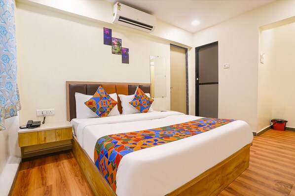 Relax in a spacious room with a large bed, nightstand, and wall-mounted air conditioning unit.