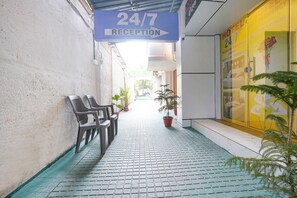 Een hotel receptie met een 24/7 bord, betegelde vloer en potplanten.