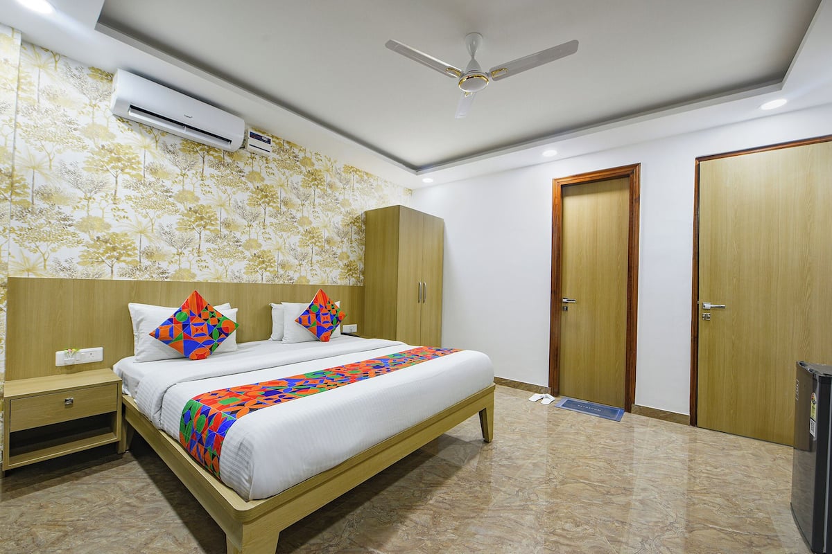 Una habitación de hotel con cama, mesita de noche, armario y ventilador de techo.