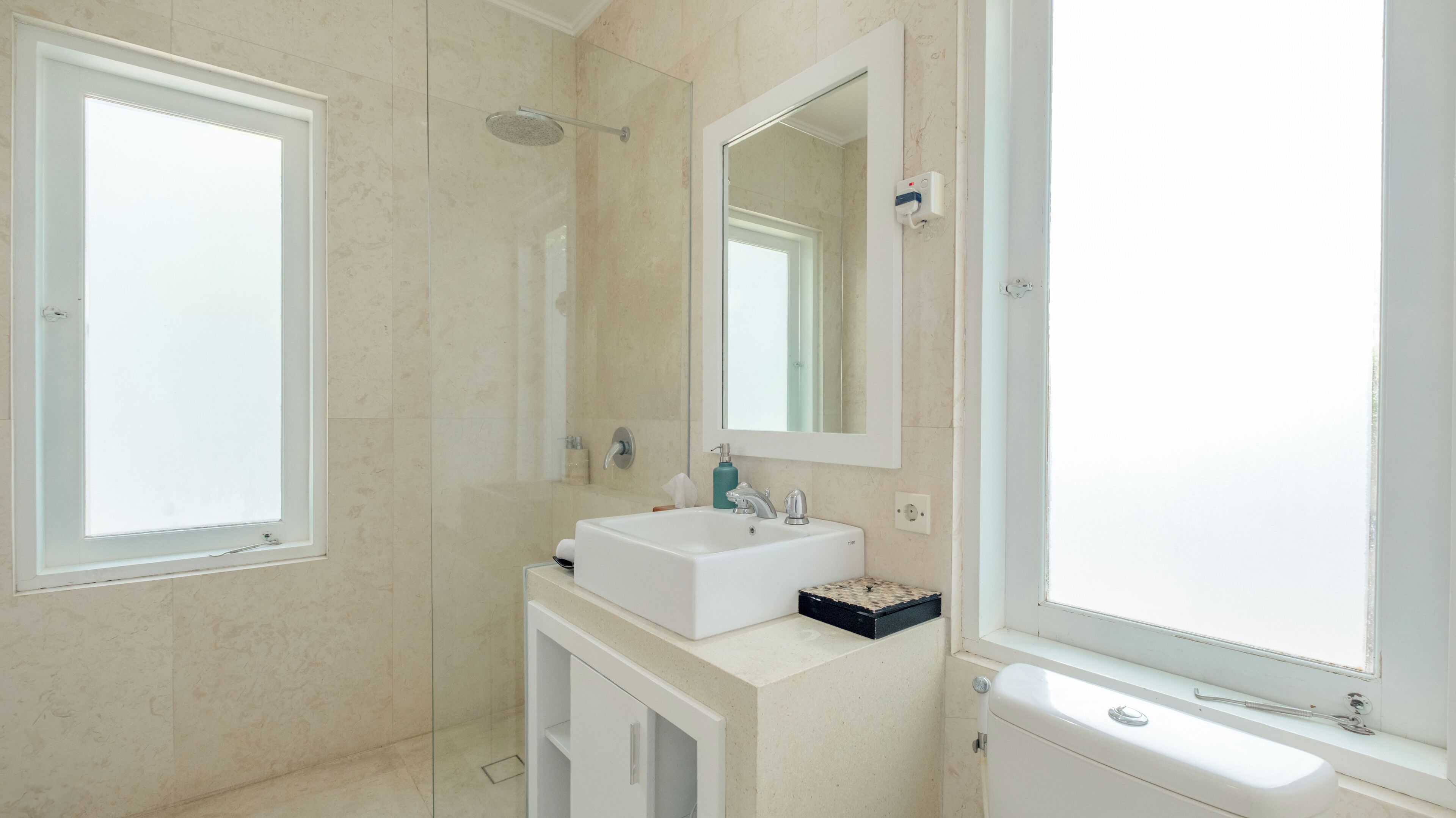 A modern bathroom with a white sink, a large mirror, and a shower.