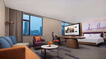 Una habitación de hotel con cama, sofá, escritorio y televisión.