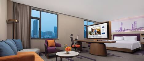 Una habitación de hotel con cama, sofá, escritorio y televisión.