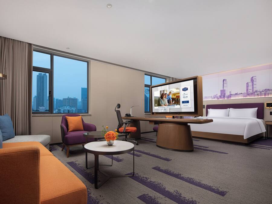 Una habitación de hotel con cama, sofá, escritorio y televisión.