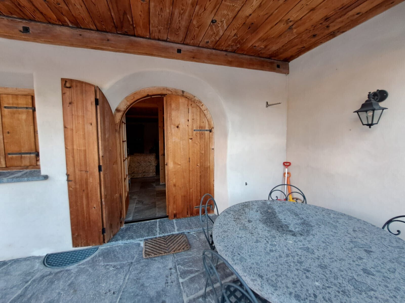 Ein rustikaler Raum mit Steinboden, Holztüren und einem Metalltisch.