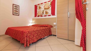 Ein Schlafzimmer mit einem Bett, einem Kleiderschrank, einem Nachttisch und einer Wand mit einem gerahmten Bild.