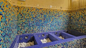 Ein Zimmer mit einer gefliesten Wand und einer blauen Badewanne mit Ablauf.