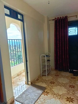 Enjoy a simple, functional space with a balcony offering a view, a patterned tile floor, and a metal shelf unit.
