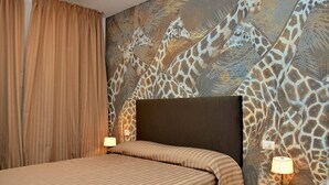 Ein Hotelzimmer mit Bett, Vorhängen, einem Kopfteil und einer Wand mit Giraffenmuster.