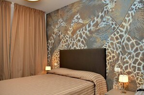 A hotel room with a bed, curtains, a headboard, and a wall with a giraffe pattern. - Charming apartment with sea-view terrace (Bibione)