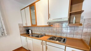 Una cocina con armarios blancos, un lavamanos de acero inoxidable, una estufa y una cafetera.