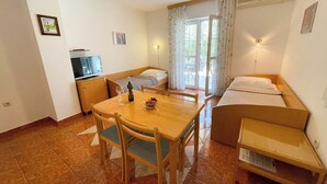 Habitación compacta con una mesa de comedor, sillas, un pequeño sofá, un televisor y una cama.
