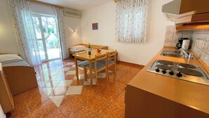 Una cocina compacta con una mesa de comedor, sillas, estufa y ventana con cortinas.