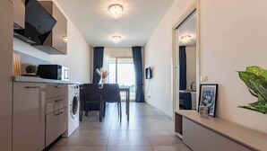 Una cocina moderna con lavadora, un comedor con sillas y un espejo grande.