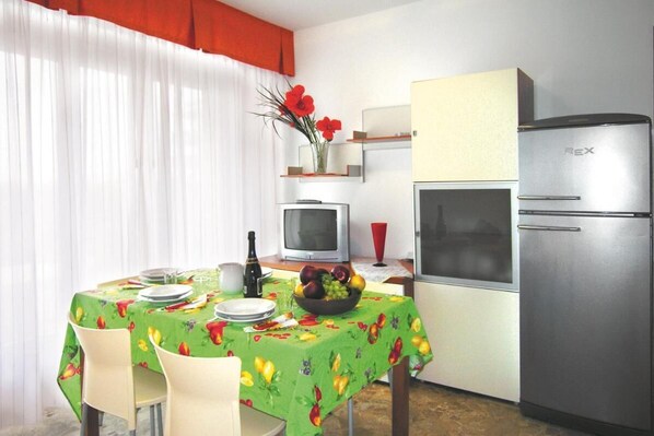 Enjoy meals for two at this cozy kitchen area, featuring a dining table, refrigerator, and TV.