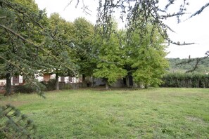 Eine Wiese mit Bäumen und einem Gebäude im Hintergrund.