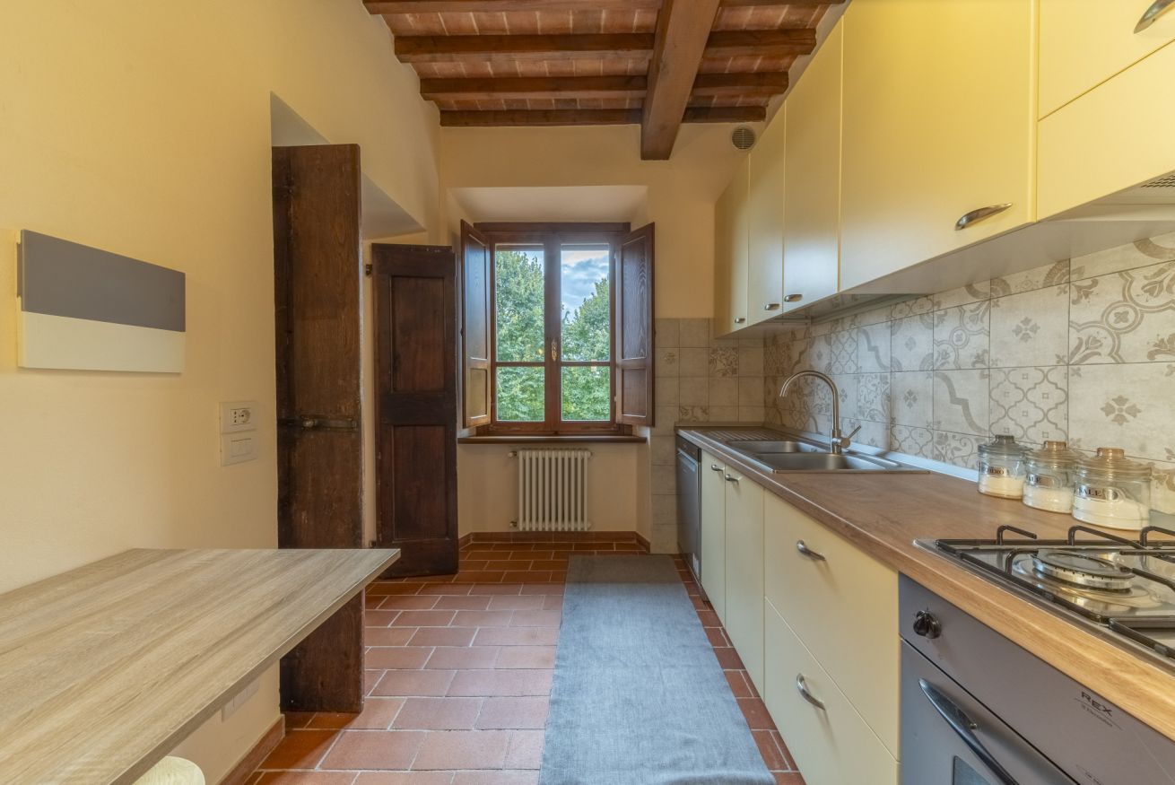 Eine Küche mit Holzausziehtisch, einem Herd, Schränken und einem Fenster mit Blick auf Grünflächen.