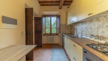 Eine Küche mit Holzausziehtisch, einem Herd, Schränken und einem Fenster mit Blick auf Grünflächen.
