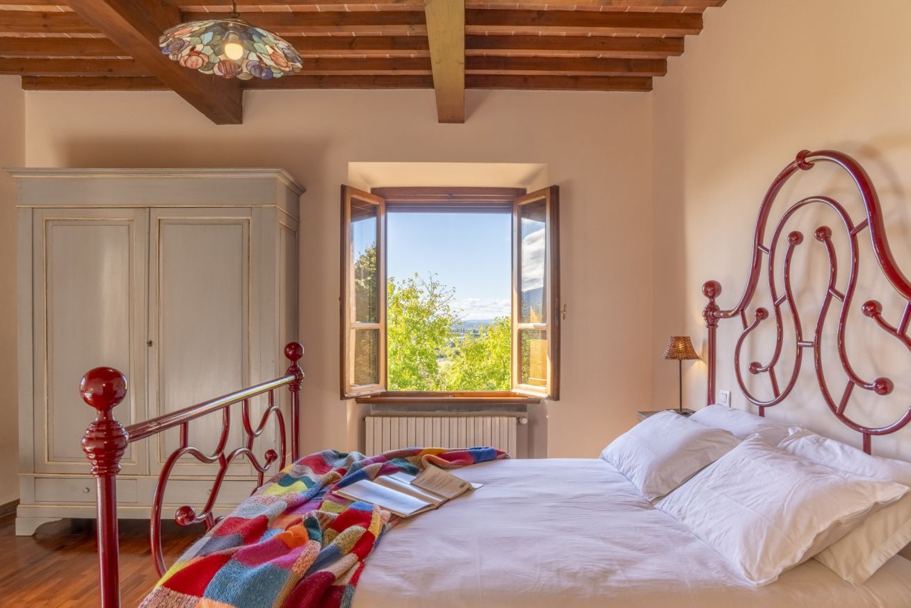 Ein Schlafzimmer mit Bett, Fenster, Kleiderschrank und einer Kristallleuchtre.