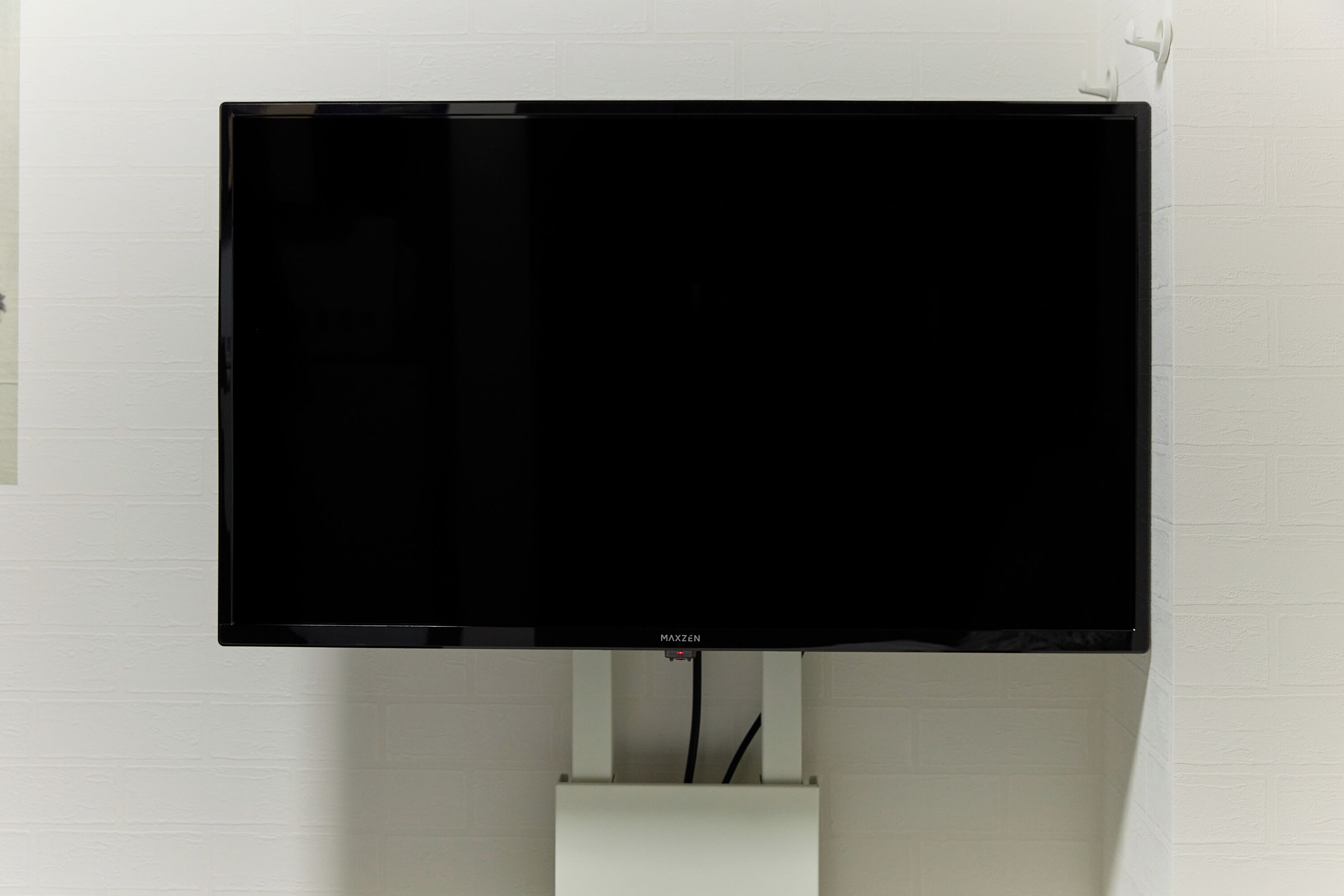 A flat-screen TV mounted on a white brick wall.