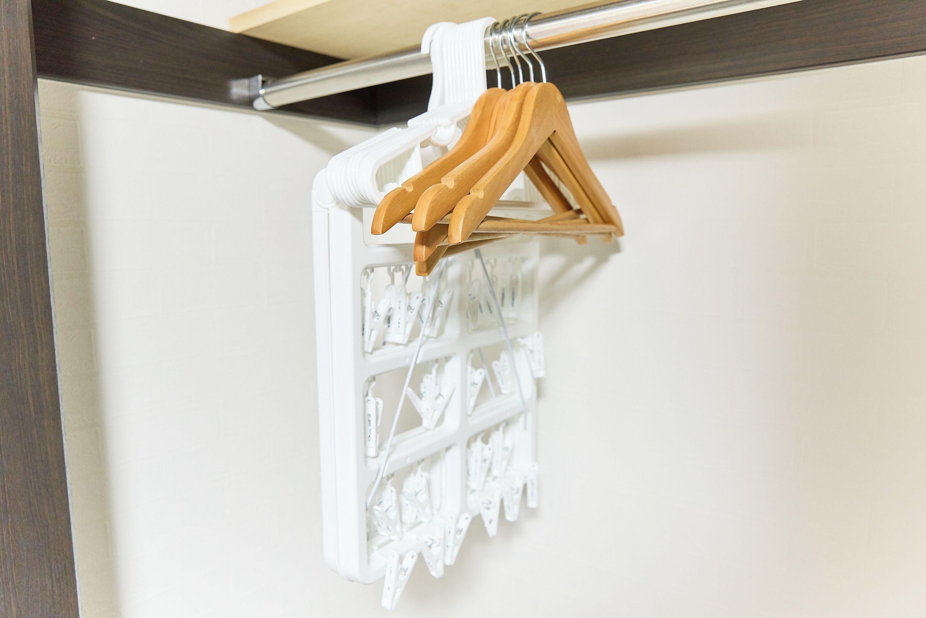 A white wall with a white hanging rack and wooden hangers.