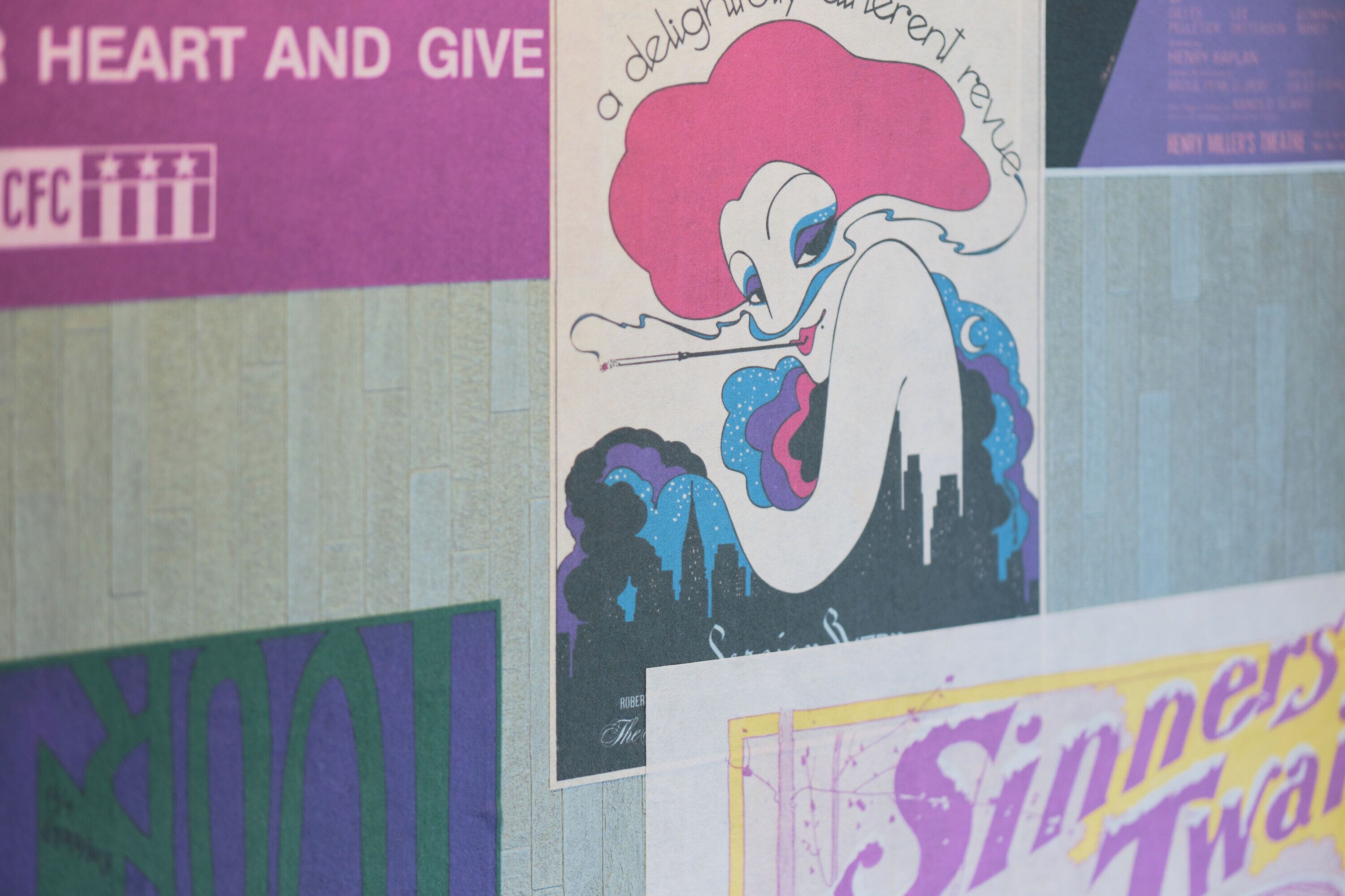 Una pared con varios carteles, incluyendo uno con un diseño rosa y azul y otro con texto.