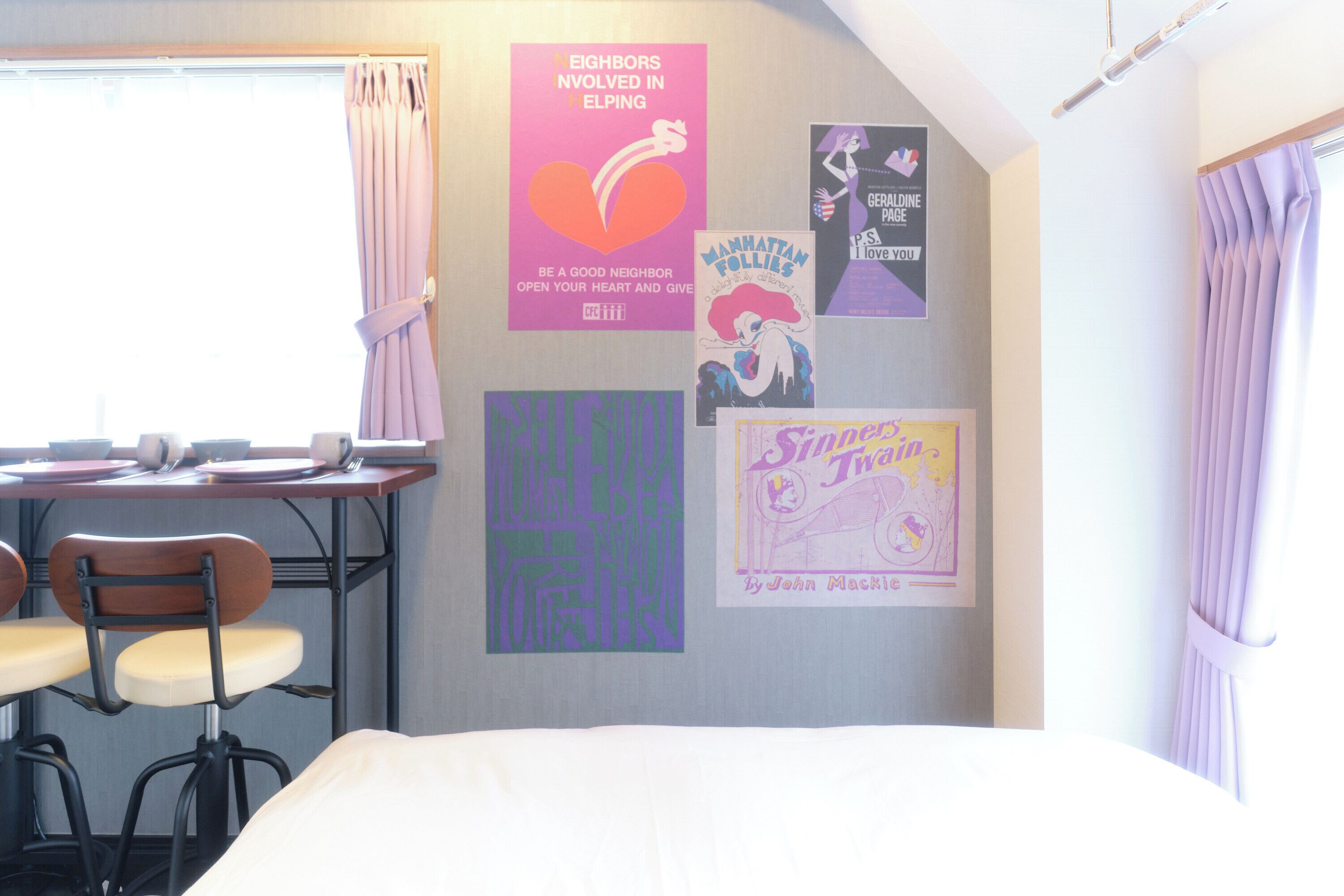 Una habitación con una cama, un escritorio con una silla y un tablón de anuncios con varios carteles.