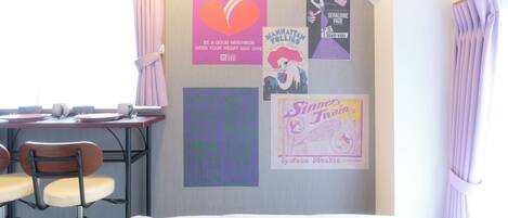 Una habitación con una cama, un escritorio con una silla y un tablón de anuncios con varios carteles.