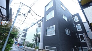 A modern building with a dark facade, multiple windows, and a visible entrance. - Marine Cove Hatsudai by Tranova (Tokyo)