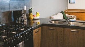 Una cocina con armarios de madera, estufa, pileta y ventana.