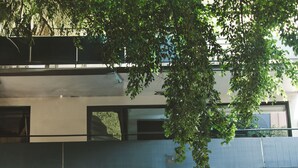 Un edificio moderno con fachada de hormigón, un pequeño árbol en la parte delantera y una puerta con cerradura electrónica.