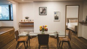 Un comedor moderno con una mesa de vidrio y sillas de madera, un jarrón con flores y obras de arte en las paredes.