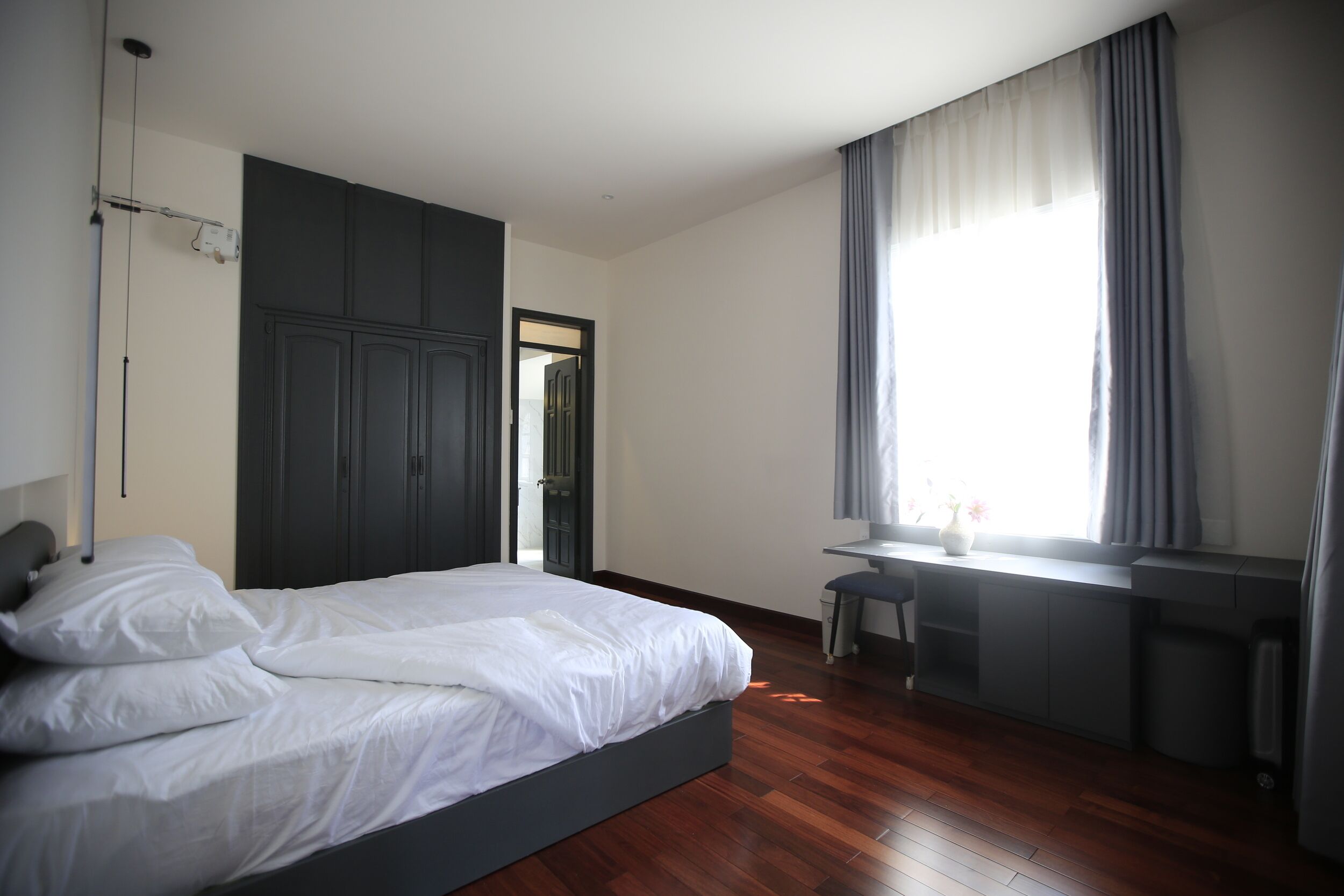 Un dormitorio con cama, escritorio y ventana con cortinas.