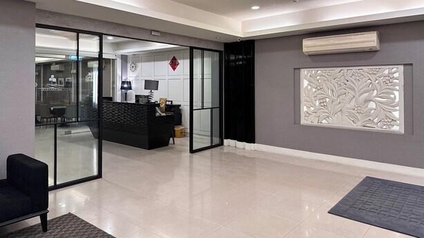 A modern hotel lobby with a glass partition, a reception desk, a chandelier, and a decorative panel. - Kaiyue Inn (Hualien City)