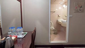A hotel room with a wooden dining table, water bottles, a kettle, and a mirror. - Kaiyue Inn (Hualien City)