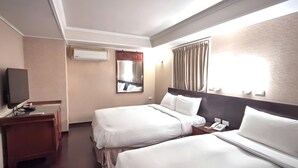 A hotel room with two beds, a desk with a telephone, a television, and a mirror. - Kaiyue Inn (Hualien City)