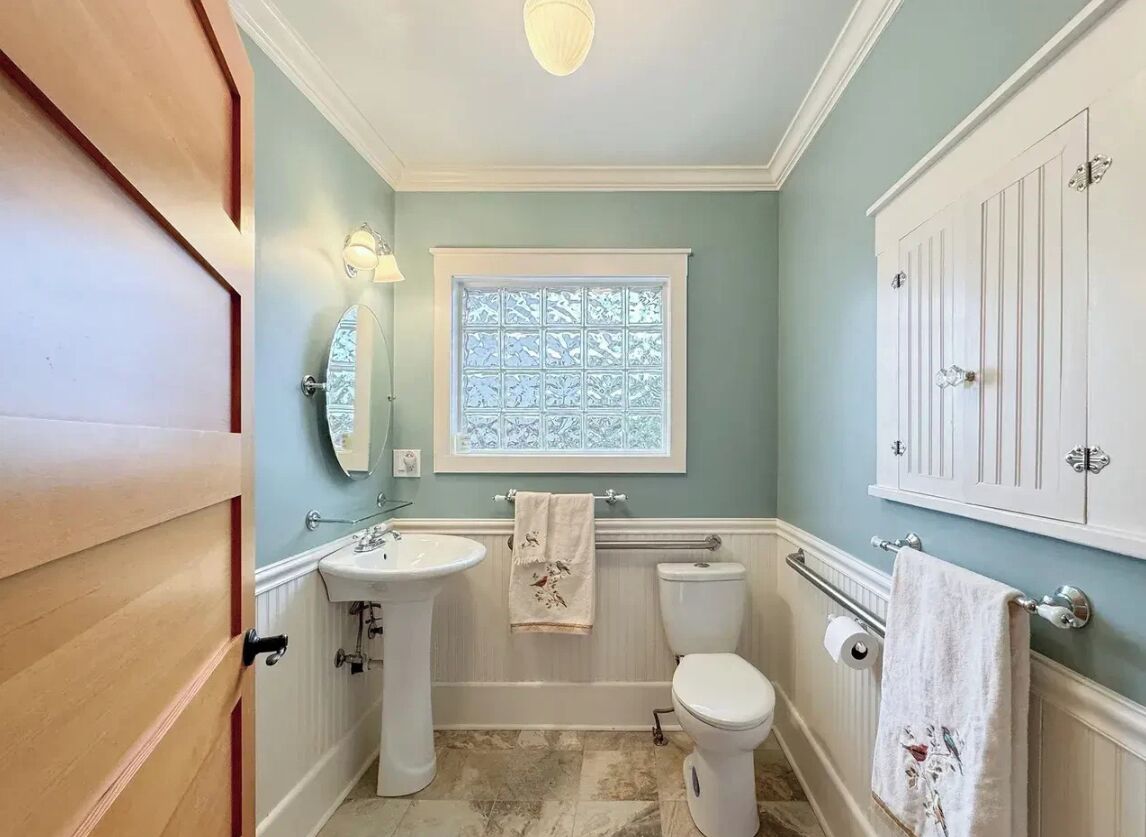 Un bagno con lavandino, WC e finestra.