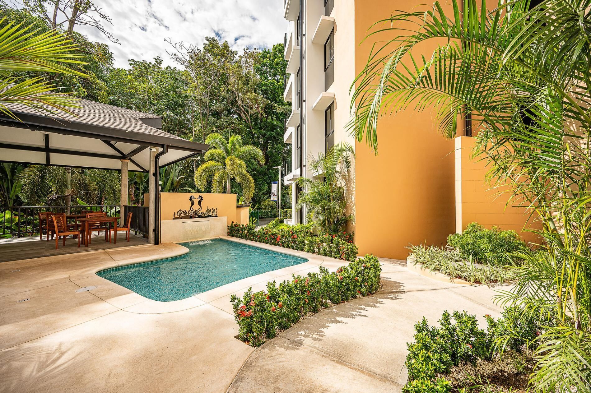Uma área de piscina com espaço de estar coberto e um painel com relevos decorativos.