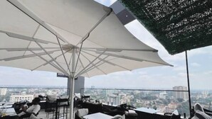 Une terrasse sur le toit avec des sièges extérieurs, un grand parasol et une vue sur la ville.