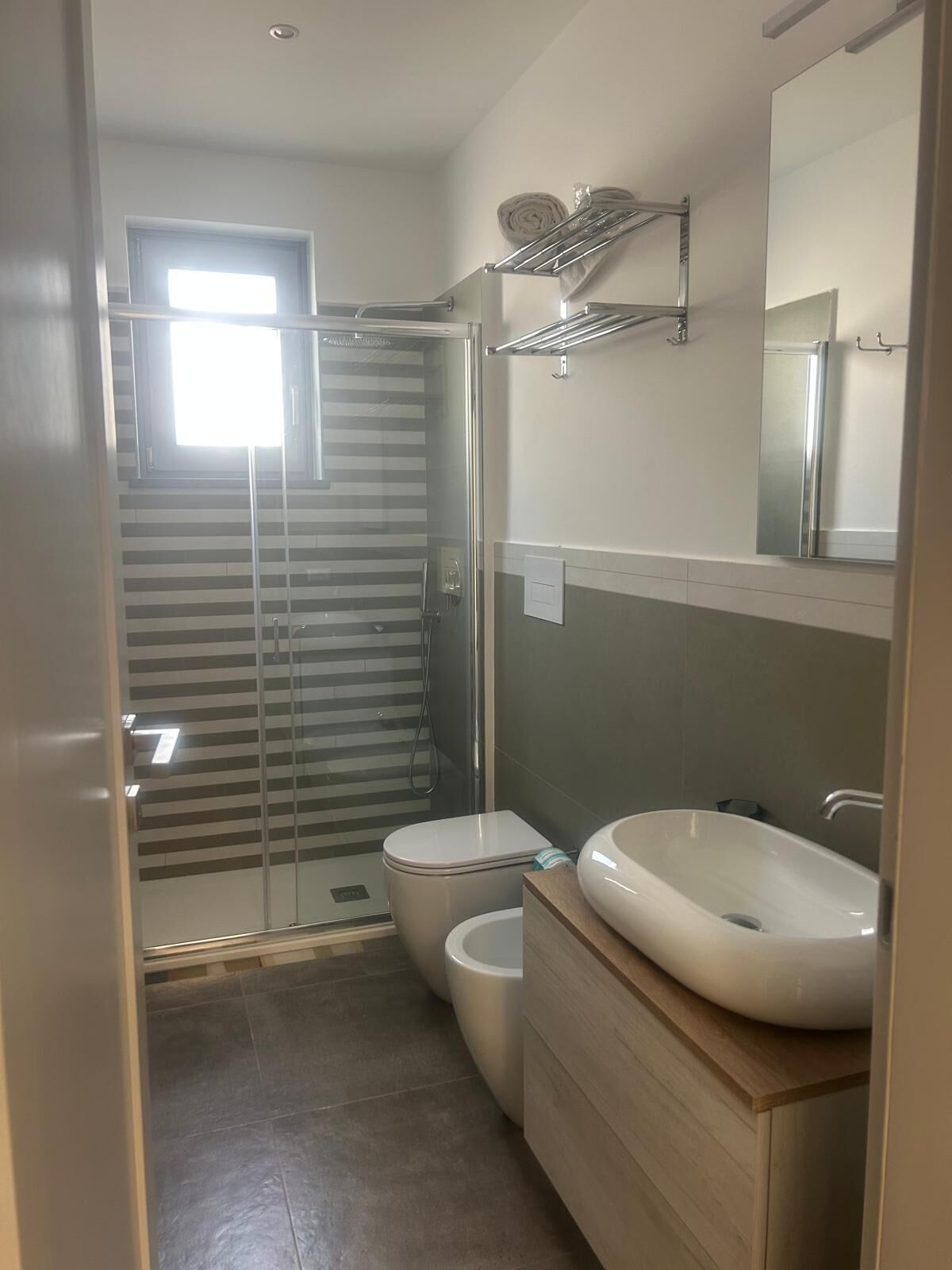 Un baño moderno con cabina de ducha de vidrio, inodoro y tocador con lavamanos.